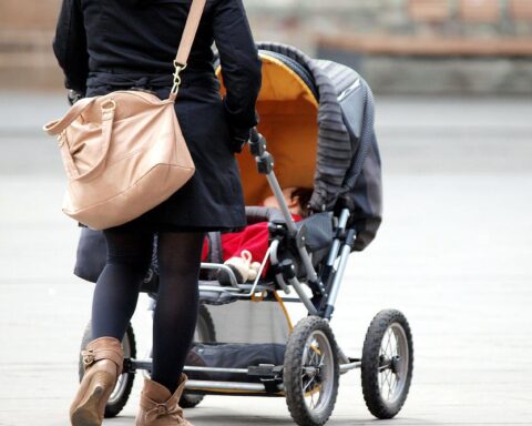 Mutter mit Kleinkind im Kinderwagen symbolisiert Unterstützung und Fürsorge in der Geburtshilfe.