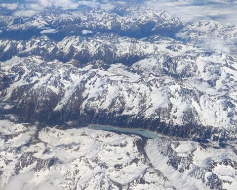 Bayerische Alpen mit Schnee, bewölkten Himmel, mildem Wetter und Sonnenstrahlen über den Regionen.