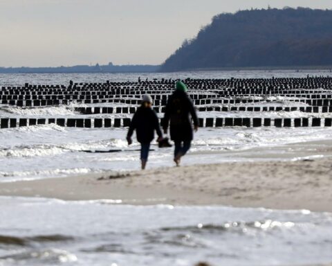 Mildes Wetter an der Küste, Wolken, Sonne, sanfte Wellen und Küstenschutzanlagen sichtbar.