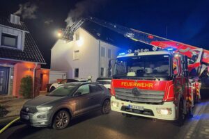 Feuerwehr löscht Zimmerbrand in Mülheim, alle Bewohner unverletzt, Einsatzkräfte vor Gebäude.