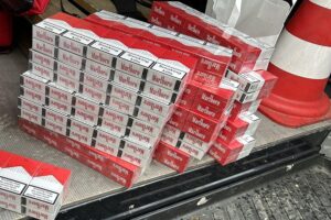 Zigarettenstapel, Geld, Smartphones und Beweismittel bei Zigarettenschmuggel-Razzia durch Zollbehörden.