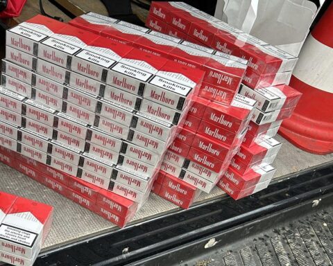 Zigarettenstapel, Geld, Smartphones und Beweismittel bei Zigarettenschmuggel-Razzia durch Zollbehörden.