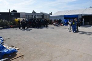 Zollbeamte kontrollieren chinesische Arbeiter in Lagerhalle, Verdacht auf illegale Beschäftigung in Deutschland.
