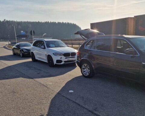 Zollbeamte kontrollieren BMW-Kolonne an Autobahn, potenzielle Steuerhinterziehung festgestellt.