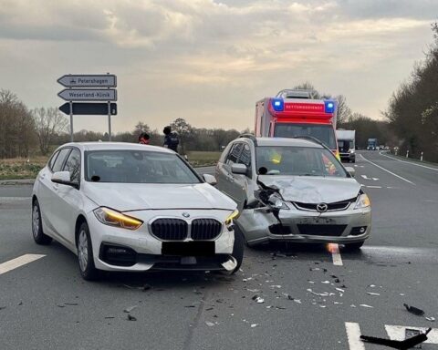 Zwei beschädigte Autos nach Verkehrsunfall auf einer Straße, Abschleppwagen im Hintergrund.