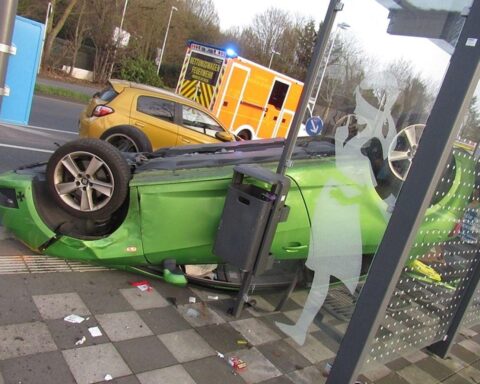 Auto auf dem Dach in Bushaltestelle, Unfallstelle mit Polizei und beschädigten Fahrzeugen.