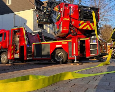 Brand in Wohnhaus, Feuerwehr im Einsatz, zwei verletzte Personen, dichter Rauch aus Fenster.