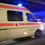 Ein Krankenwagen an einer Unfallstelle mit beschädigten Fahrzeugen und Feuerwehr im Einsatz.