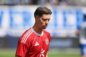 Fußballspiel mit jubelnden Spielern, Ergebnisanzeigen und leidenschaftlichen Fans im Stadion.