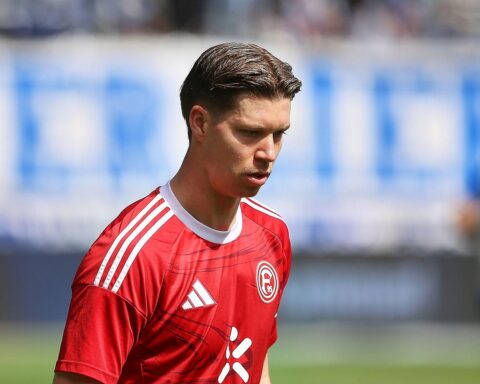 Fußballspiel mit jubelnden Spielern, Ergebnisanzeigen und leidenschaftlichen Fans im Stadion.