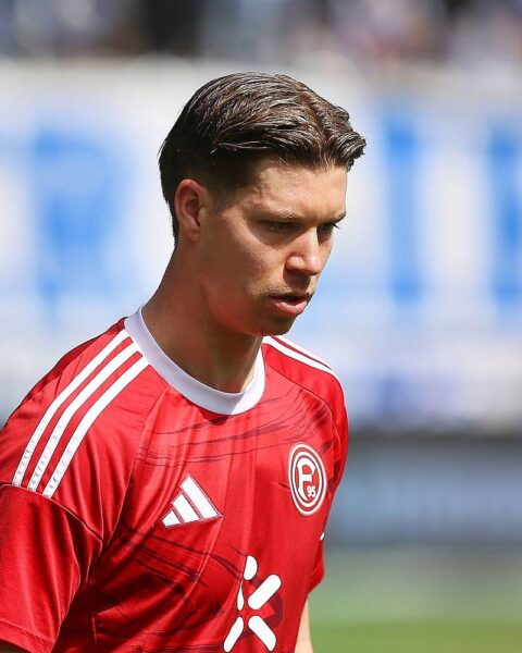 Fußballspiel mit jubelnden Spielern, Ergebnisanzeigen und leidenschaftlichen Fans im Stadion.