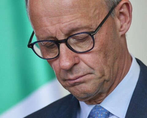 Friedrich Merz bei einer politischen Veranstaltung mit dem ZDF-Logo und Umfrageergebnissen im Hintergrund.