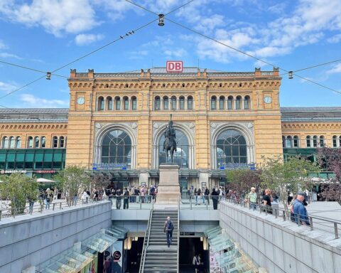 Hannover Hauptbahnhof mit prominenter Ankündigung des Alkoholkonsumverbots. Verantwortliche Personen stehen im Vordergrund.