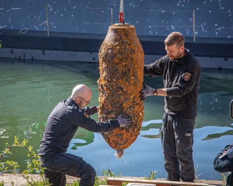 Zwei Männer vom Kampfmittelräumdienst verladen erfolgreich entschärfte Bombe vom Baggerschiff an Land.
