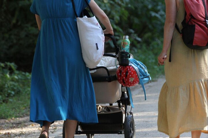 Zwei Frauen mit Kinderwagen im Park, symbolisieren Elternschaft und Elterngeld in Deutschland.