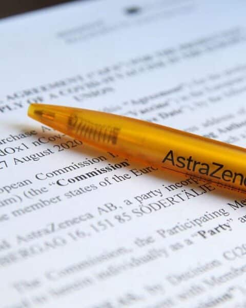 Vertragshandshake zwischen EU und AstraZeneca, symbolisiert Kooperation und Herausforderungen im Gesundheitssystem.