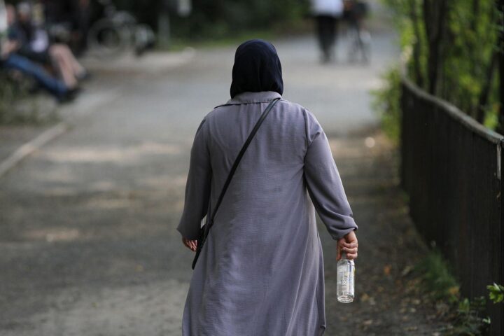 Frau mit Kopftuch in urbaner Umgebung, symbolisiert Vielfalt und Migration in Nordrhein-Westfalen.
