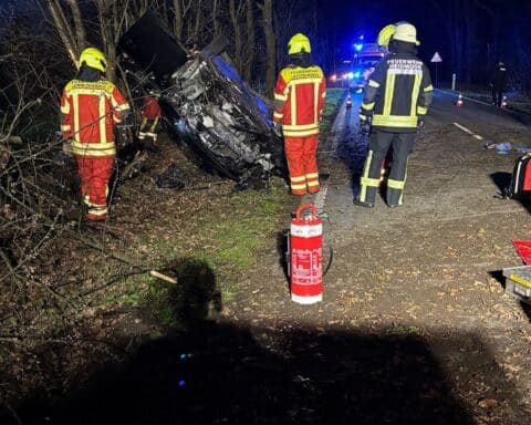 Verunfallter PKW liegt auf dem Dach, Einsatzkräfte retten Person aus Fahrzeug.