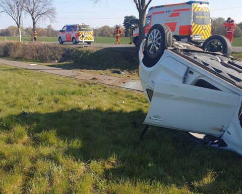 Ein verunglücktes Auto auf dem Kopf, umgeben von Bäumen und Unfallort-Szenario.