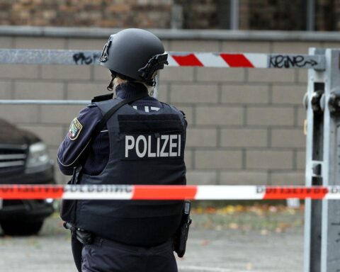 Polizistin hinter Absperrband bei Unfallstelle, Unfallaufnahme und Rettungsarbeiten im Gange.