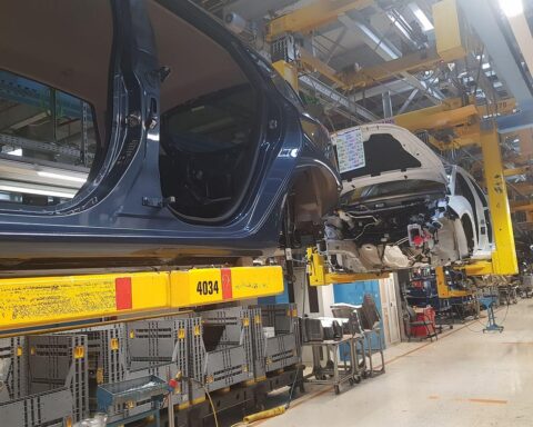 Elektrische Autos auf Produktionslinie, BYD-Logo, Fabrikarbeiter arbeiten an Fahrzeugen in modernem Werk.