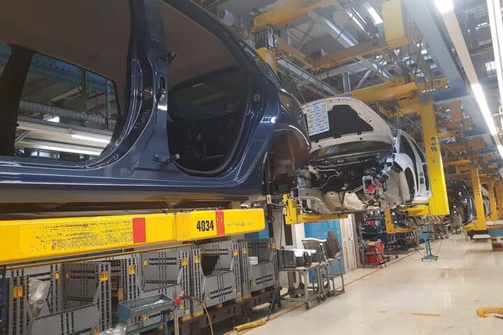 Elektrische Autos auf Produktionslinie, BYD-Logo, Fabrikarbeiter arbeiten an Fahrzeugen in modernem Werk.