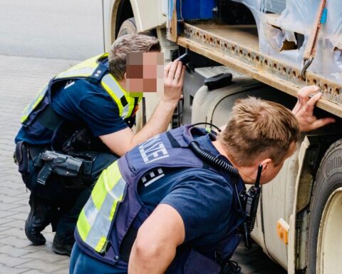 Polizei und Zoll kontrollieren Lastwagen auf Parkplatz, zeigen Verstöße im gewerblichen Verkehr auf.
