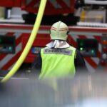 Spielplatzbrand in Osnabrück: Flammen, beschädigter Pkw und Feuerwehr im Einsatz.
