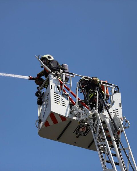 Feuerwehr löscht Brand in Gartenlaube, Einsatzkräfte und Rauchwolken sichtbar.
