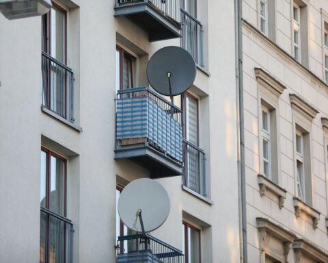 Auf dem Bild ist eine Satellitenschüssel an einem Wohnhaus zu sehen.
