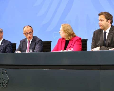 Konferenzraum mit CDU, CSU und SPD Spitzenpolitikern diskutierend über Energiesofortprogramm und Preissenkungen.