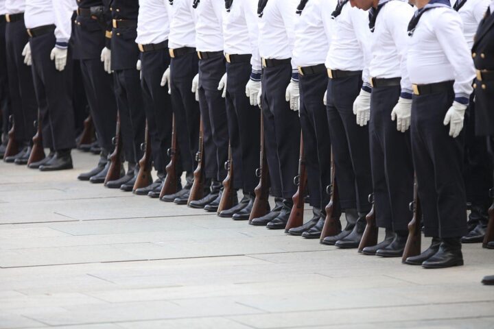 Ein Marine-Soldat in Uniform, bereit für den Wechsel, mit Schiffen im Hintergrund.