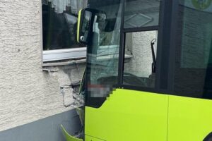 Ein Linienbus prallt gegen eine Hauswand, Sachschaden sichtbar, keine Verletzten.