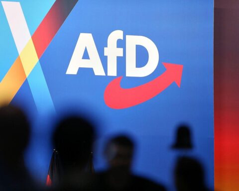 AfD-Logo vor dem Hintergrund eines CDU-Parteitags in ländlicher Ostdeutschlandregion.