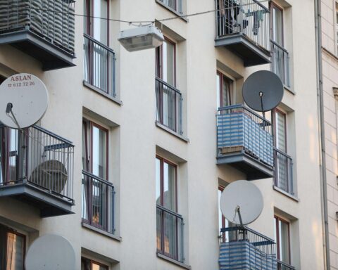 Satellitenschüssel an Wohnhaus symbolisiert aktuelle Wohnraumsituation und soziale Ungerechtigkeiten in Deutschland.