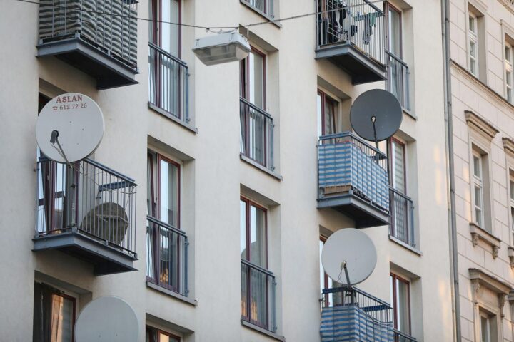 Satellitenschüssel an Wohnhaus symbolisiert aktuelle Wohnraumsituation und soziale Ungerechtigkeiten in Deutschland.