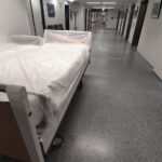 Krankenhaus mit Ärzten, Krankenpflegern und einem Patienten; symbolisiert die GKV-Reformdiskussion.