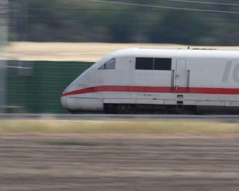 Ein ICE trifft pünktlich am Bahnhof ein, umgeben von Reisenden und Fahrplänen.