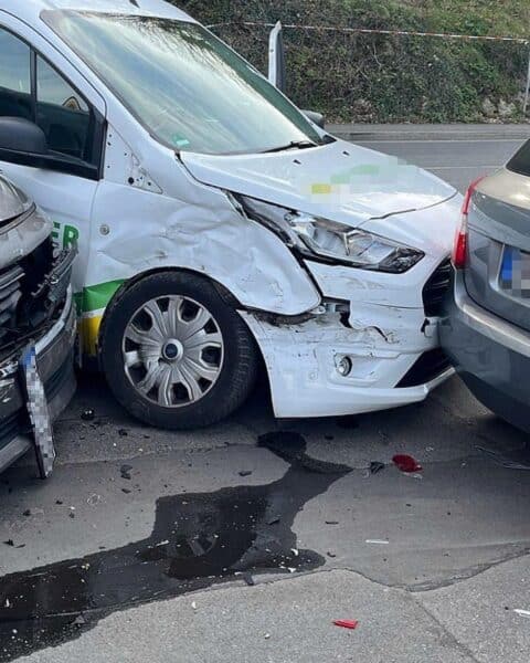 Unfallstelle mit beschädigten Fahrzeugen, Polizei und Rettungskräften, leicht verletzte Personen werden versorgt.