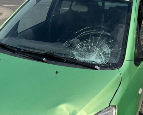 Unfall zwischen Elektroroller und Pkw auf einer Straße, Verletzter und Fahrzeugschäden sichtbar.