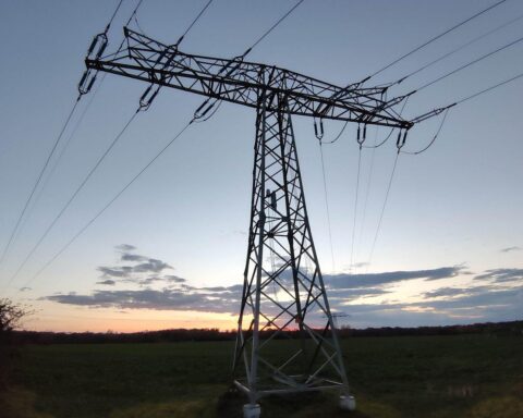 Strommast vor blauem Himmel, Symbol für Energiepreise und industrielle Unterstützung in Krisenzeiten.
