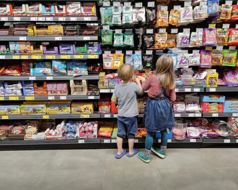 Kinder im Supermarkt beobachten Produkte, symbolisieren Konsumverhalten in Zeiten sinkender Einzelhandelsumsätze.