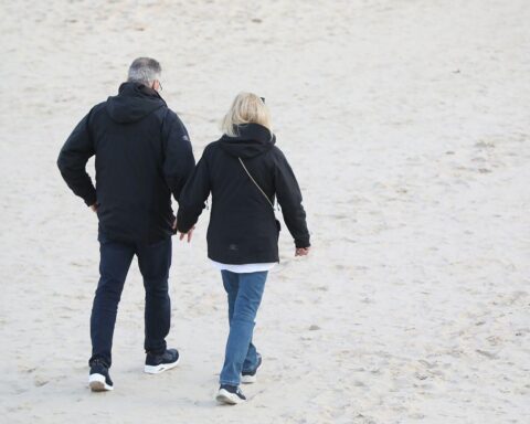 Paar spaziert am Strand, symbolisiert Beziehung und Unterstützung in der aktuellen Gesundheitsdebatte.