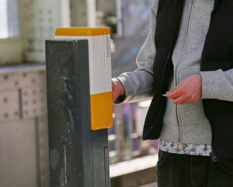 Ein Fahrgast stempelt eine Fahrkarte in einem öffentlichen Verkehrsmittel, symbolisiert Ticketkontrolle.