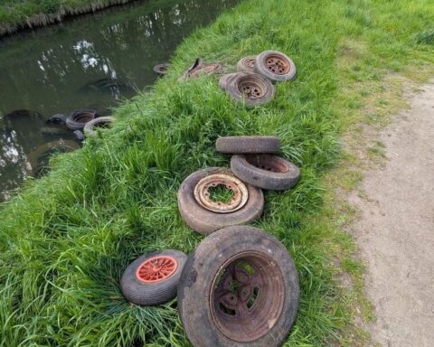 Illegal entsorgte Altreifen am Flussufer, Gefahr für Wasserqualität und Umweltverschmutzung.
