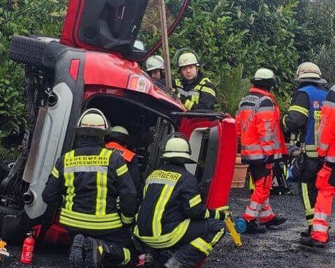 Feuerwehr rettet eingeklemmte Frau aus umgekipptem SUV nach Verkehrsunfall auf Parkplatz.
