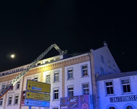 Feuerwehr im Einsatz bei Großbrand in Geschäftsgebäude, Flammen und Drehleitern sichtbar.