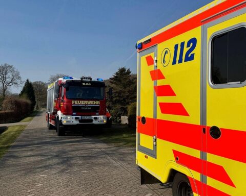 Feuerwehr öffnet Tür für Rettungsdienst und unterstützt beim Transport einer hilfsbedürftigen Frau.