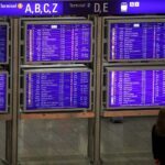 Frau vor Informationstafel am Frankfurter Flughafen, symbolisiert steigende Passagierzahlen und neues Terminal.