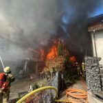 Feuerwehrlöscharbeiten bei Garagenbrand; starke Rauchentwicklung, angrenzendes Wohnhaus gefährdet.
